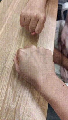 two people are sitting at a table and one person is cutting something with a knife