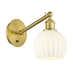 an antique brass wall light with a white glass globe shade