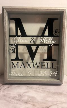 a framed wedding sign with the initials and date printed on it in black, white, and silver