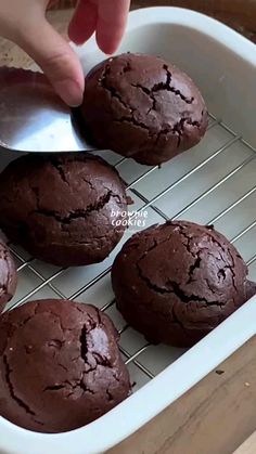 chocolate cookies cooling on a wire rack with a person scooping out the top one