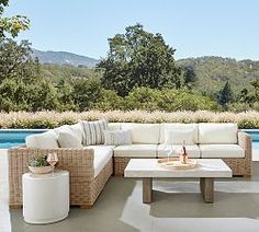 an outdoor living room with white furniture next to a pool