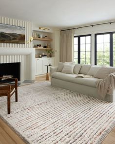 a living room with a couch, fireplace and large rug in front of the window