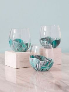 three glasses with marbled designs on them sitting on a table