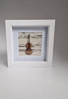 a violin with sheet music on it in a white frame