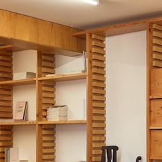 a wooden book shelf with many books on top of it and two chairs in front of it