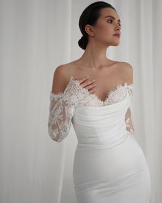 a woman wearing a white dress with long sleeves and an off the shoulder lace top