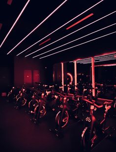 there are many bikes lined up in the room with red lights on them and black flooring