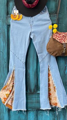 a cowboy hat, jeans and purse hanging on a wooden door with blue painted wood planks