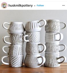 five white coffee mugs are stacked on top of each other, one is made out of ceramic