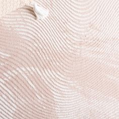 an up close view of the textured fabric on a bed sheet that is pink and white