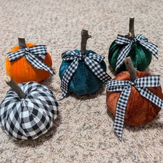 four pumpkins with bows on them sitting on the floor in front of a carpet