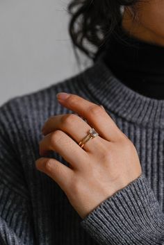 a woman's hand with a ring on her finger and a turtle neck sweater