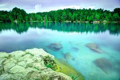 the water is crystal blue and green with rocks in it's foreground, surrounded by trees