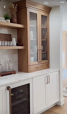 a kitchen with white cabinets and wooden shelves filled with dishes, glasses and wine bottles