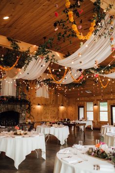 a room with tables and chairs covered in white draping, flowers and candles