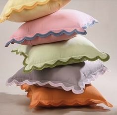 a stack of pillows sitting on top of each other in different colors and sizes with scalloped edges