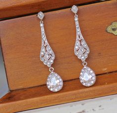 "Elegant 'modern-vintage' Bridal earrings have been designed in a delicate open-work style studded with cubic zirconium crystals with a crystal teardrop, to add a gorgeous delicate sparkle to your wedding day. Set in tarnish resistant 18K Rhodium (White Gold Plate) with high quality cubic zirconium crystals for heirloom quality. Allergy free. L = 1 3/4\" (4.5 cm) Our model wears our store sample ear post. ★Shopping for your bridal party? Contact us for special pricing. Please read our shop polic Wedding Diamond Filigree Earrings, Wedding Filigree Diamond Earrings, Wedding Diamond Earrings With Filigree Detail, Wedding Diamond Earrings With Filigree, Teardrop Diamond Pierced Earrings For Wedding, Pierced Teardrop Diamond Earrings For Weddings, Vintage Pierced Diamond Earrings For Wedding, Vintage Wedding Diamond Earrings, Pierced, Ornate Wedding Diamond Drop Earrings