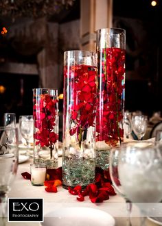 the centerpieces are filled with red flowers and candles for an elegant wedding reception