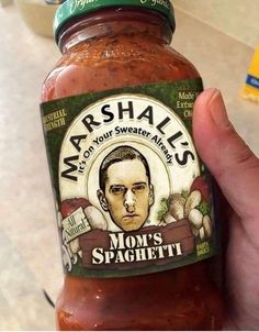 a hand holding a jar of margheris sauce