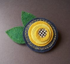 a close up of a flower made out of felt with green leaves and dots on it