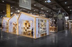 a small house made out of bookshelves in a large room with lights on the ceiling