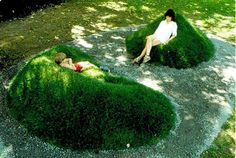 two people sitting on top of green bushes