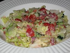 a salad with tomatoes, lettuce and other vegetables in it on a white plate