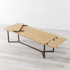 a wooden table sitting on top of a hard wood floor next to a white wall