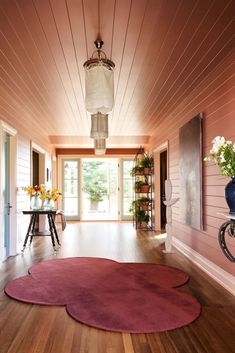 a living room with pink walls and wooden floors, two round rugs on the floor