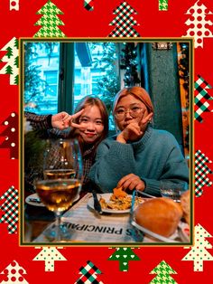 two people sitting at a table with food in front of them and christmas trees on the background