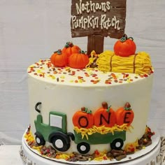 a birthday cake decorated with pumpkins, hay and a tractor