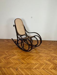 a rocking chair sitting on top of a hard wood floor next to a white wall