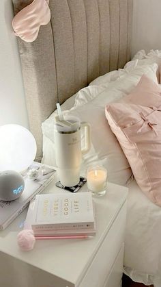 a bed with pink pillows and books on top of it next to a night stand