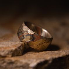 Mokume Gane is one of the most beautiful materials we offer at Patrick Adair Designs. This ring is handmade from an intricate composite hand forged in the USA. Our luxury grade Mokume Gane is an extraordinary composite of nickel silver, brass, and copper. This gives it a beautiful wood grain pattern that shows a wide variety of colors ranging from beautiful and luxurious golds to bright and brilliant copper hues. The unique compositing process combined with the hand faceted finish creates a trul Customized Rings, Mens Engagement Ring, Mokume Gane Ring, Wedding Band Gold, Carbon Fiber Rings, Rings Mens, Copper Jewellery, Sterling Silver Jewelry Rings, Engagement Ring Unique