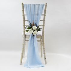 a chair with a blue sash and flowers on the back is set against a white backdrop