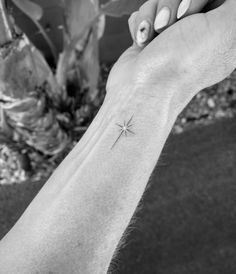 a person's arm with a small star tattoo on the left side of their wrist