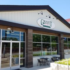 the front of a restaurant with tables and chairs outside