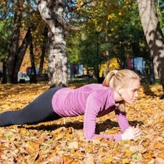 a woman is doing push ups in the leaves