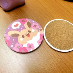 a wooden table topped with two coasters and a pink mouse on top of it