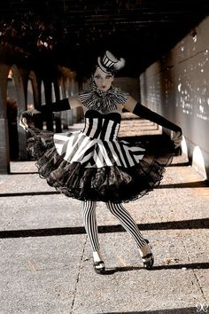 a woman dressed in black and white is walking down the street with her legs spread out