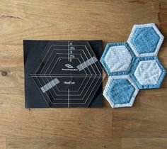 two hexagons sitting on top of a wooden table next to a piece of paper