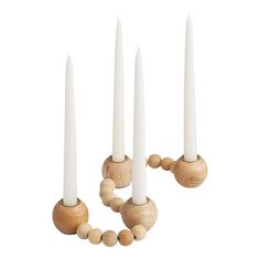 three white candles with wooden beads on each candle holder and one is turned upside down