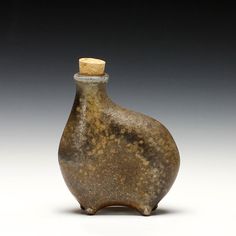 a brown vase with a cork top sitting on a table