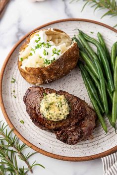 steak, potatoes and green beans on a plate with rosemary sprigs next to it