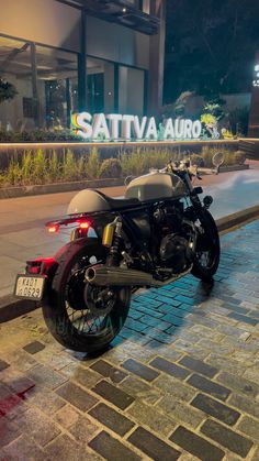 a motorcycle is parked on the side of the road near a sign that says sattva auto