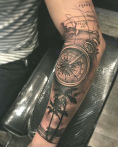 a man's arm with a compass and palm trees on the inside of it