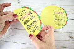 two people holding up some yellow paper with writing on them and one has a taco