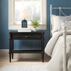 a bedroom with blue walls, white bedding and a black night stand in front of the window