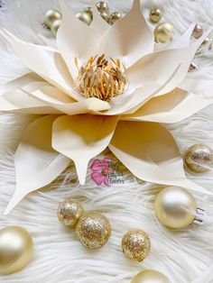 a large white flower sitting on top of a fur covered floor next to christmas ornaments