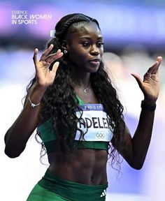 a female athlete is holding her hands up in the air while wearing a green outfit